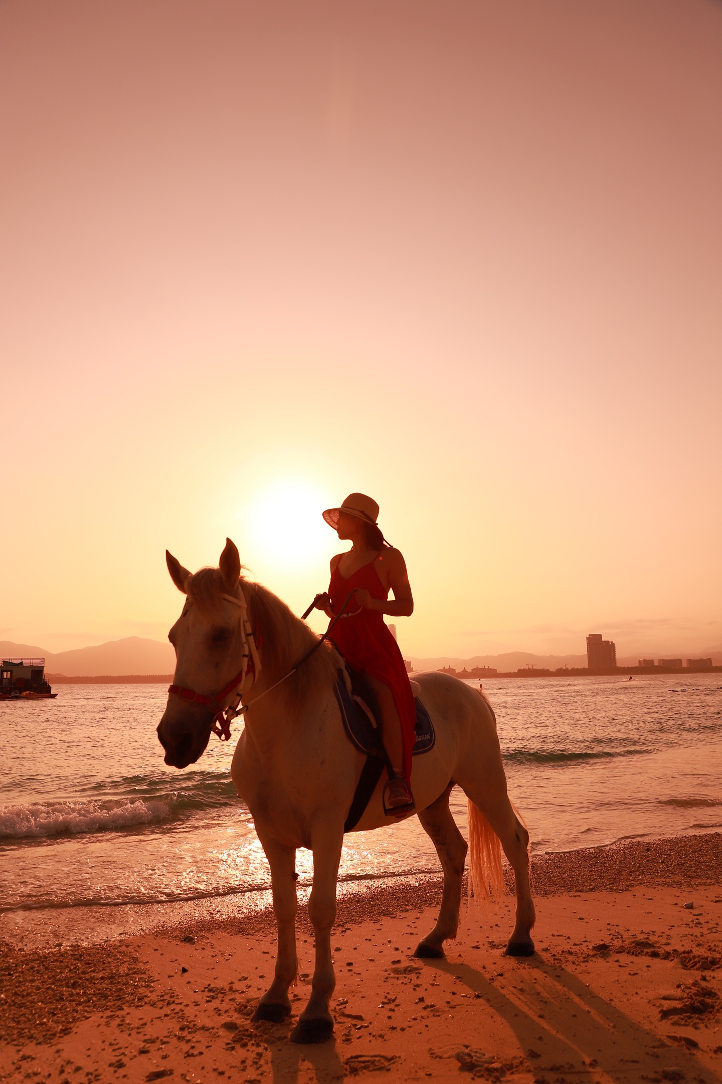 夕阳余晖,海滩上的白马和红衣女子眺望远方最浪漫的晚餐,情人桥的听海